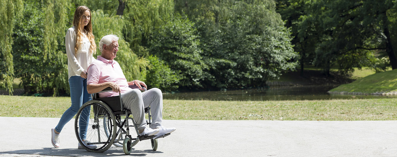 Polnische Pflegerin bei gemeinsamer Aktivität, in Form von Ausflug und Spaziergang mit Rollstuhl.